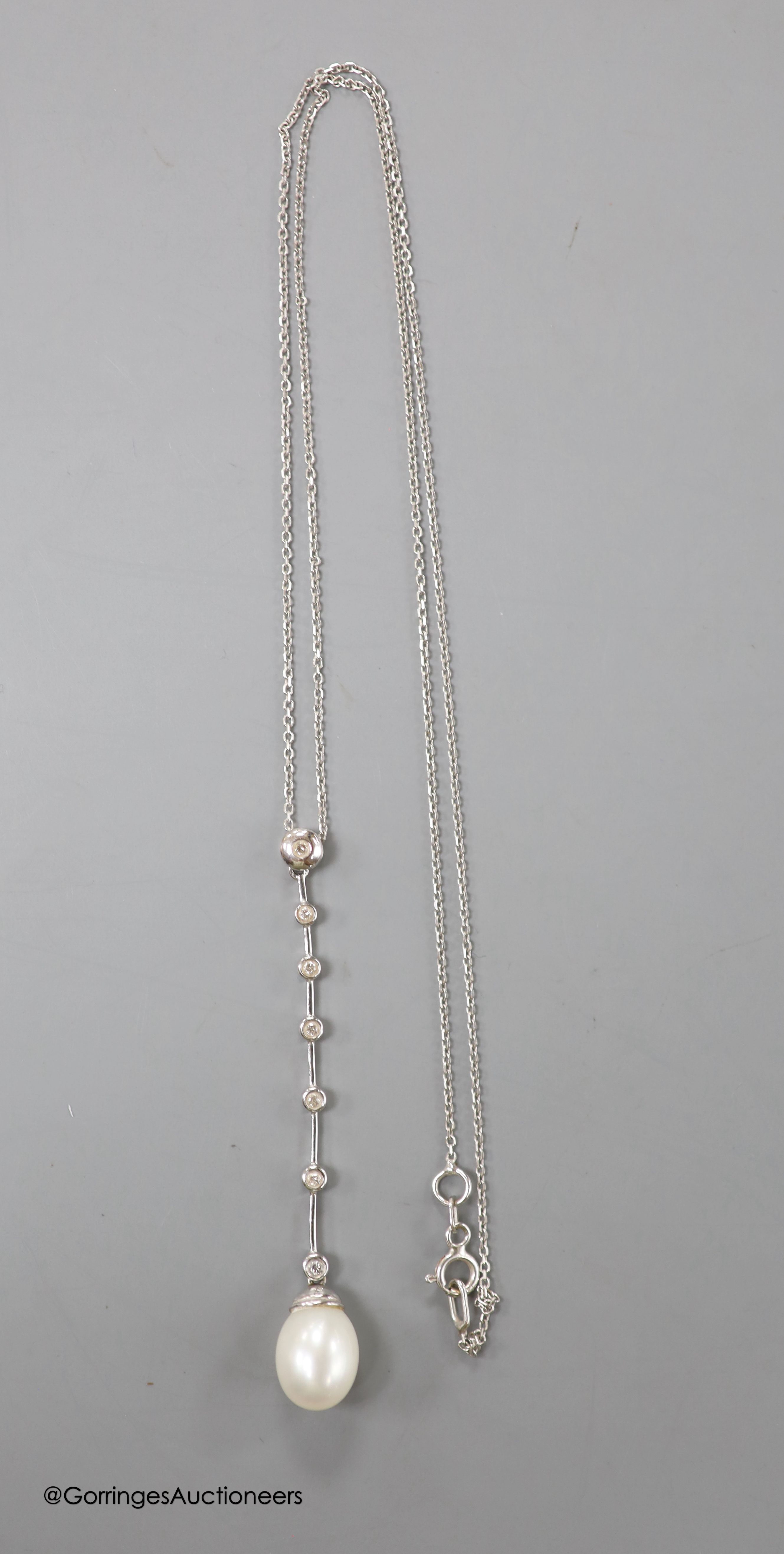 A modern white metal (stamped 14kt), cultured pearl and seven stone diamond chip set drop line pendant necklace, pendant 6cm, chain, 45cm, gross weight 4.1 grams.
